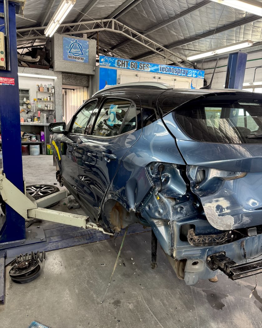 Auto con la parte trasera chocada, esperando la reparación de chapa