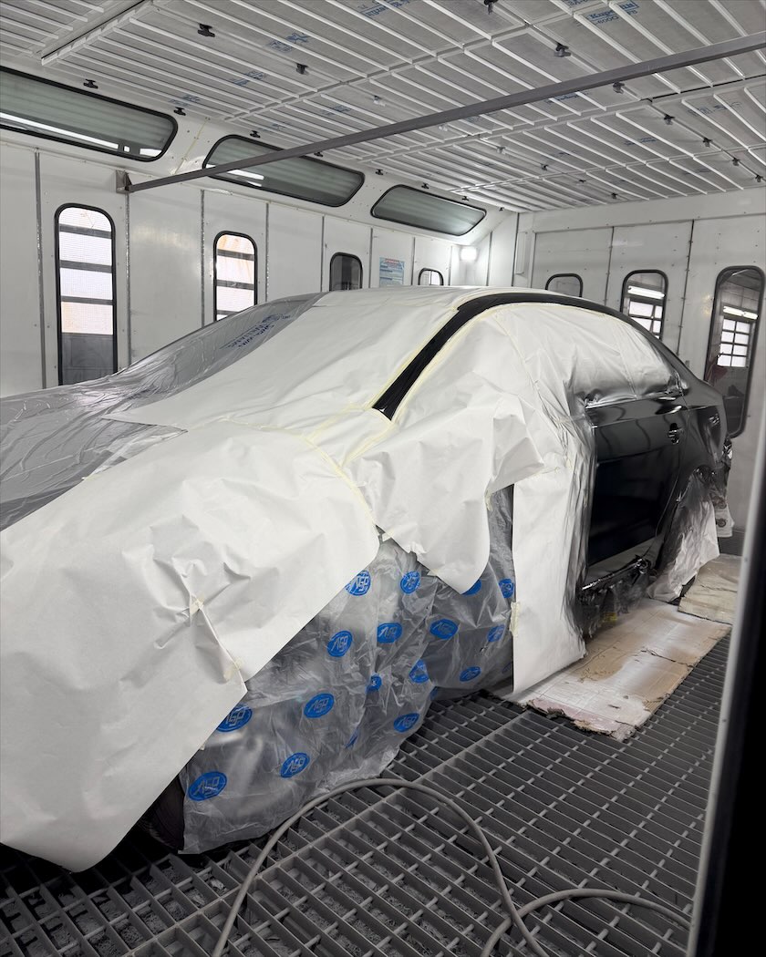 Auto cubierto y encintado dentro de la cabina de pintura