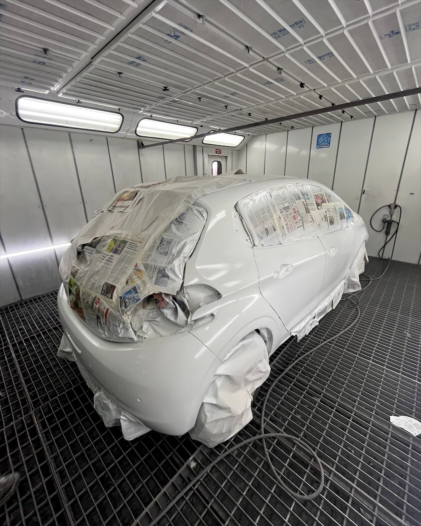 Auto blanco preparado para pintar en la cabina