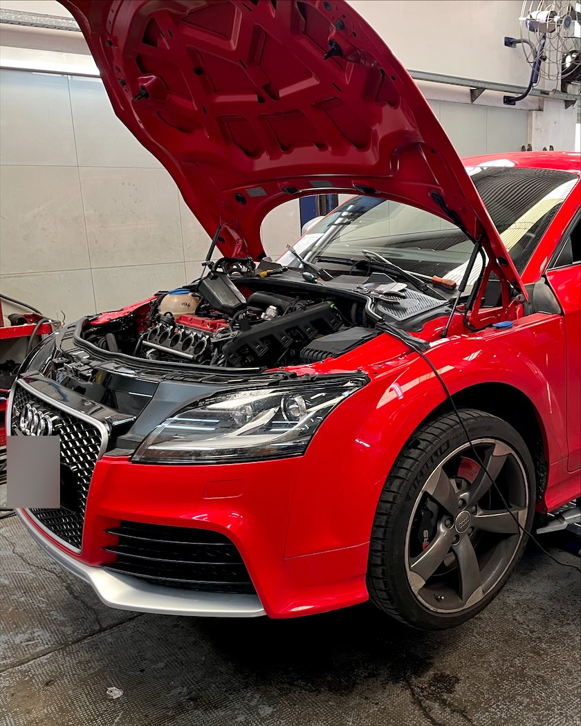 Audi TT con el capó abierto sobre el elevador del taller